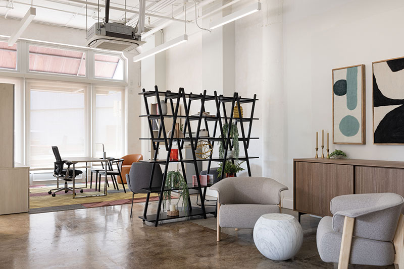 Another angle of the seating area; this time with more view in to the area with the swivel chair and the two modern seats. In the photo, behind the left cushioned seat of seating area there is a bookshelf holding decorative objects, books, and plants.