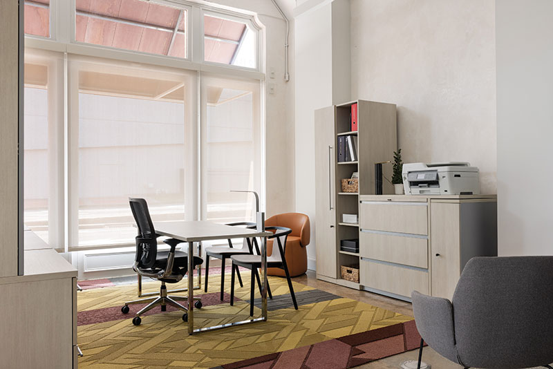 Another angle of the first section in first photo. This angle reveals that behind the two modern chairs, there is a shelf with binders as well as a printer. There is also an orange chair in the far corner.