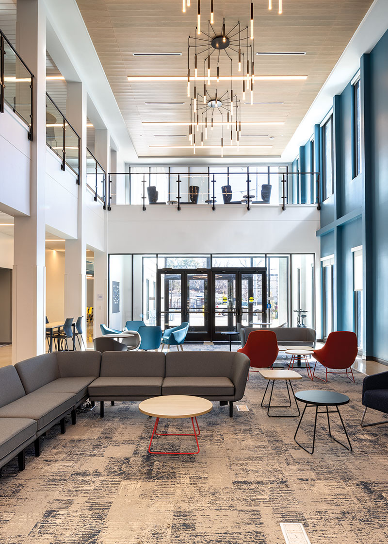 Another angle of the space, showcasing two levels of the four story building. There is another sectional and more comfortable blue chairs with plenty of tables to use.